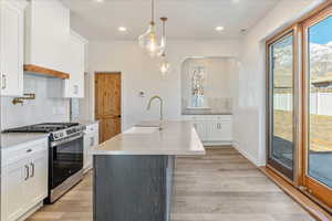 Kitchen featuring stainless steel range with gas cooktop, light countertops, a center island with sink