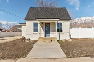 Bungalow-style house featuring a shingled roof, fence, a mountain view, and stucco siding