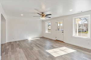 Foyer entrance with light wood-type flooring, visible vents, ceiling fan, and baseboards