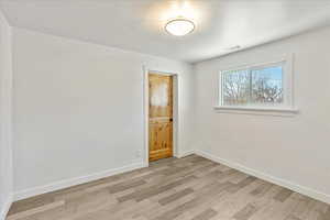 Empty room featuring visible vents, light wood-style flooring, and baseboards