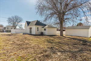 Back of house featuring a lawn, fence, and central AC