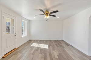 Entrance foyer with arched walkways, light wood finished floors, and baseboards