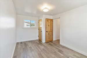 Unfurnished bedroom with light wood finished floors, visible vents, and baseboards