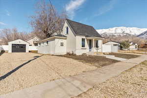 Bungalow featuring a garage, gravel driveway, covered porch, an outdoor structure, and a mountain view