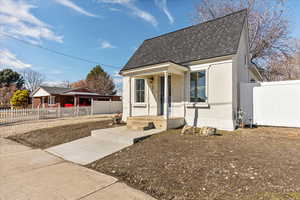 Bungalow-style house with a fenced front yard, roof with shingles, and stucco siding