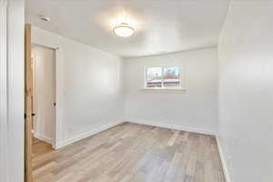 Spare room with light wood finished floors, visible vents, and baseboards