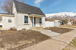 View of front of property featuring a shingled roof, fence, a mountain view, and stucco siding