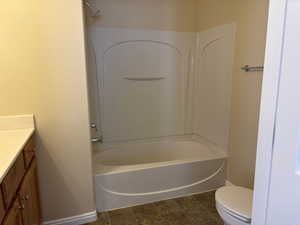 Full Master bathroom featuring baseboards, toilet, vanity, tile patterned floors, and shower/bathtub combination