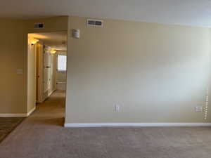 Unfurnished room with baseboards, visible vents, and light colored carpet