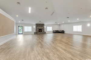 Unfurnished living room featuring light wood-style floors, a fireplace, visible vents, and a wealth of natural light