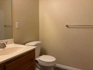 Half bathroom featuring baseboards, vanity, toilet, and tile patterned floors