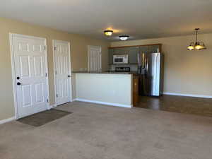 Kitchen with dark countertops, a peninsula, stainless steel appliances, dark carpet, and pendant lighting