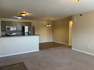 Kitchen with visible vents, hanging light fixtures, appliances with stainless steel finishes, dark carpet, and dark countertops