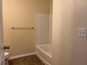 Full bathroom with toilet, a bathtub, baseboards, and tile-patterned flooring