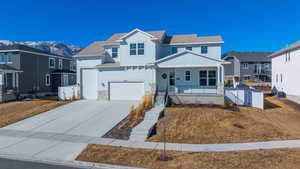 View of front of property featuring covered porch, concrete driveway, an attached garage, a mountain view, and a residential view