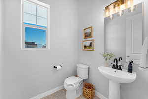 Half bath featuring toilet, baseboards, and speckled floor