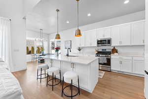 Kitchen with appliances with stainless steel finishes, light countertops, a sink, and white cabinetry