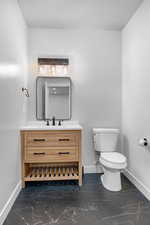 Bathroom with toilet, marble finish floor, baseboards, and vanity