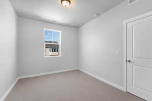 Unfurnished room with visible vents, baseboards, a textured ceiling, and light colored carpet