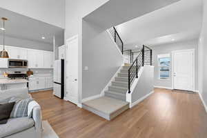 Living room featuring light wood-type flooring, recessed lighting, baseboards, and stairs