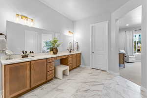 Bathroom featuring double vanity, marble finish floor, baseboards, and a sink