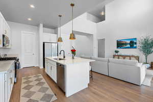 Kitchen with stainless steel appliances, white cabinetry, light countertops, and open floor plan