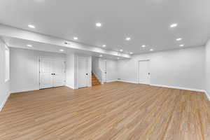 Finished basement with recessed lighting, visible vents, stairway, light wood-type flooring, and baseboards