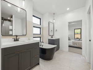 Ensuite bathroom with ensuite bathroom, two vanities, a sink, and a healthy amount of sunlight