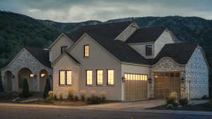 View of front facade featuring stucco siding, a mountain view, a garage, stone siding, and driveway