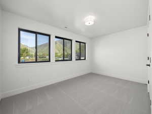 Empty room with visible vents, carpet flooring, a mountain view, and baseboards