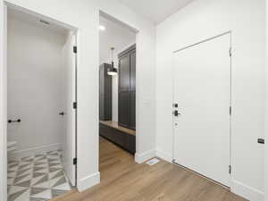 Foyer with light wood-type flooring, baseboards, and visible vents