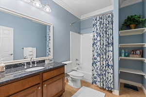 Full bathroom featuring crown molding, toilet, shower / bath combo with shower curtain, vanity, and tile patterned floors