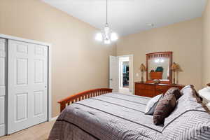 Bedroom with light carpet and a chandelier