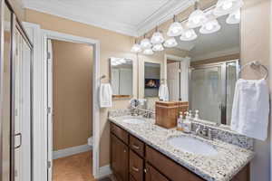 Full bathroom with a shower stall, ornamental molding, and a sink