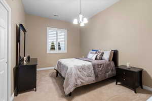 Bedroom with a chandelier, light carpet, visible vents, and baseboards