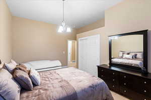 Bedroom with a closet, a notable chandelier, and light colored carpet