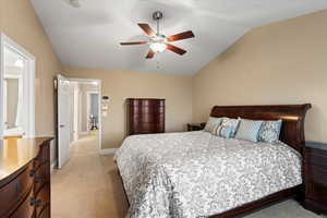 Bedroom with a ceiling fan, lofted ceiling, light carpet, and baseboards