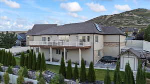 Rear view of property with an outbuilding, a mountain view, a storage shed, stone siding, and stucco siding