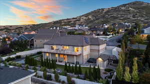 Back of property at dusk featuring a fenced backyard, a mountain view, stone siding, a residential view, and stucco siding