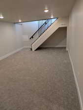 Basement with carpet floors, visible vents, stairway, and baseboards