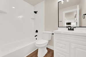 Bathroom featuring baseboards, toilet, vanity, wood finished floors, and shower / bathtub combination