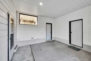 Empty room featuring brick wall and unfinished concrete floors