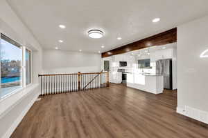 Interior space featuring a textured ceiling, recessed lighting, dark wood-style flooring, visible vents, and baseboards