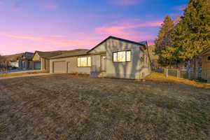 View of front of house featuring driveway, an attached garage, a gate, fence, and a front lawn