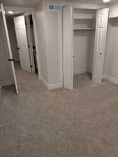 Unfurnished bedroom with baseboards, visible vents, a closet, and light colored carpet