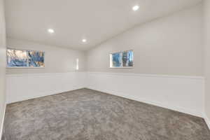 Carpeted empty room featuring lofted ceiling, baseboards, and recessed lighting