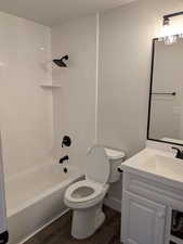 Bathroom featuring a textured ceiling, toilet, wood finished floors, vanity, and  shower combination