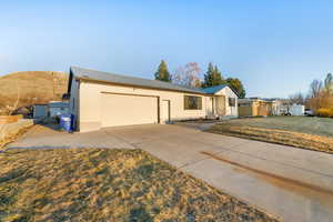 Single story home with a garage, concrete driveway, brick siding, and a front lawn