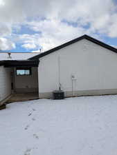 View of snow covered exterior featuring brick siding and central air condition unit