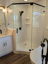 Full bath with a soaking tub, a stall shower, wood finished floors, and vanity